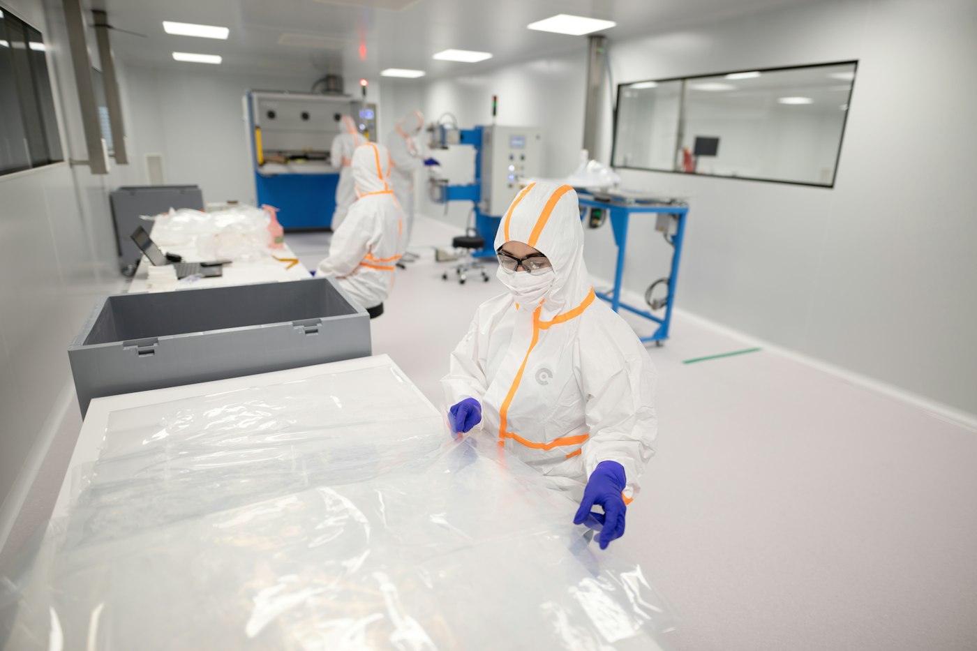Technicians in protective suits working in a cleanroom