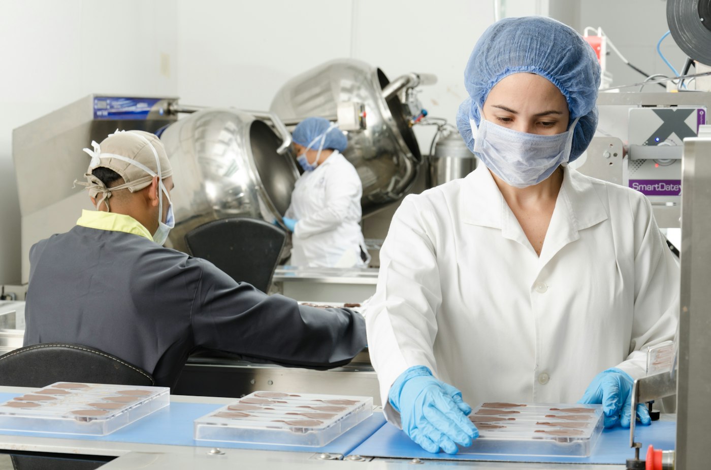 Technicians handling product trays in a pharmaceutical production area